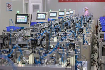 8月14日,在贛州訊康電子科技,工作人員從T1-T2全自動穿環機旁走過,該機器生產磁性元器件。新華社記者 才揚 攝